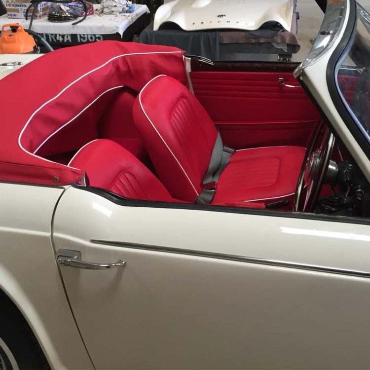 Triumph TR4A fitted with Bright Red Interior Trim Panels, Leather Seat Covers, and Hood Frame Cover.
